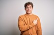 © Krakenimages.com - Young blond handsome man with curly hair wearing casual sweater over white background Pointing aside worried and nervous with forefinger, concerned and surprised expression