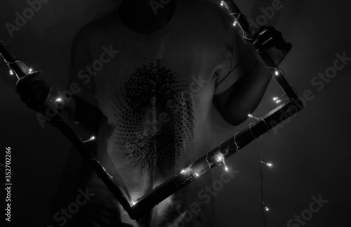Cuadros en Lienzo Midsection Of Young Man Holding Illuminated Frame In Darkroom