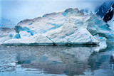 Fototapeta  - Snowing Floating Blue Iceberg Arch Reflection Paradise Bay Skintorp Cove Antarctica