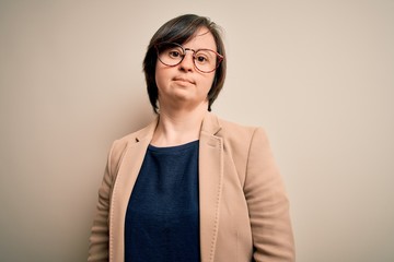 Canvas Print - Young down syndrome business woman wearing glasses standing over isolated background Relaxed with serious expression on face. Simple and natural looking at the camera.