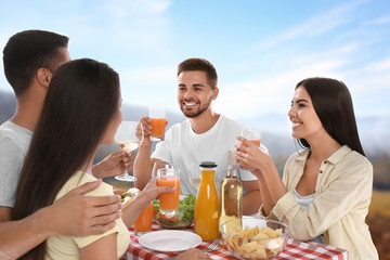 Wall Mural - Group of friends having picnic at table in park