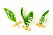 Lily of the valley flowers on a light background. Small spring bouquets are attached to the background with a medical patch. Creative minimalism, flat lay.