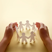 Paper People Surrounded By Hands In Gesture Of Protection. Concept Of Insurance, Social Protection And Support.