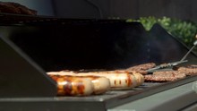 Pan Of Someone Flipping Burgers And Sausages