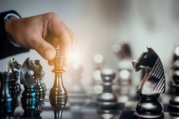 Wall Mural - Businessman moving chess piece and think strategic to win game. Chess board game concept for ideas and competition and strategy, business success concept