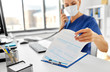 © Syda Productions - medicine, people and healthcare concept - female doctor or nurse wearing face protective medical mask for protection from virus disease with computer and clipboard calling on phone at hospital
