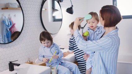 Wall Mural - Mother with small children in pajamas in bathroom at home, brushing teeth.