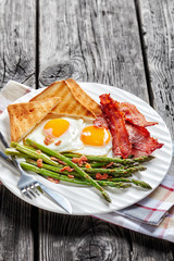 Wall Mural - a portion of fried eggs, bacon, toasts, asparagus