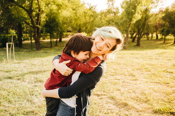 Happy young mother playing and having fun with her little baby son on sunshine. Happy family concept