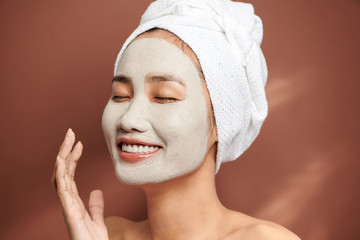 Wall Mural - Happy young woman smiling and wearing white towel and has a facial mask.