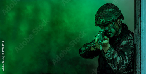 Fotografía Soldier action with gun on hand holding to protect, survey around safety area in soldier mission with white smoke background