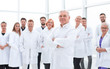 © ASDF - senior doctor standing in front of a group of medical staff.
