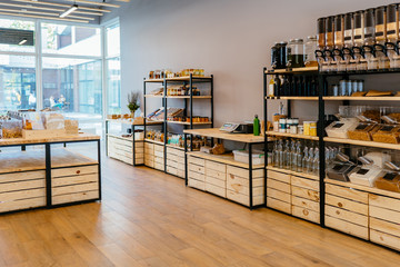 Zero waste shop interior details. Wooden shelves with different food goods and personal hygiene or cosmetics products in plastic free grocery store. Eco-friendly shopping at local small businesses.