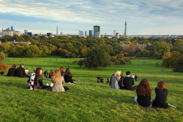 People resting on Primrose Hill at sunset, London, UK