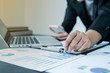 © Orathai - business female is sitting at a desk and calculating financial graph that show results
