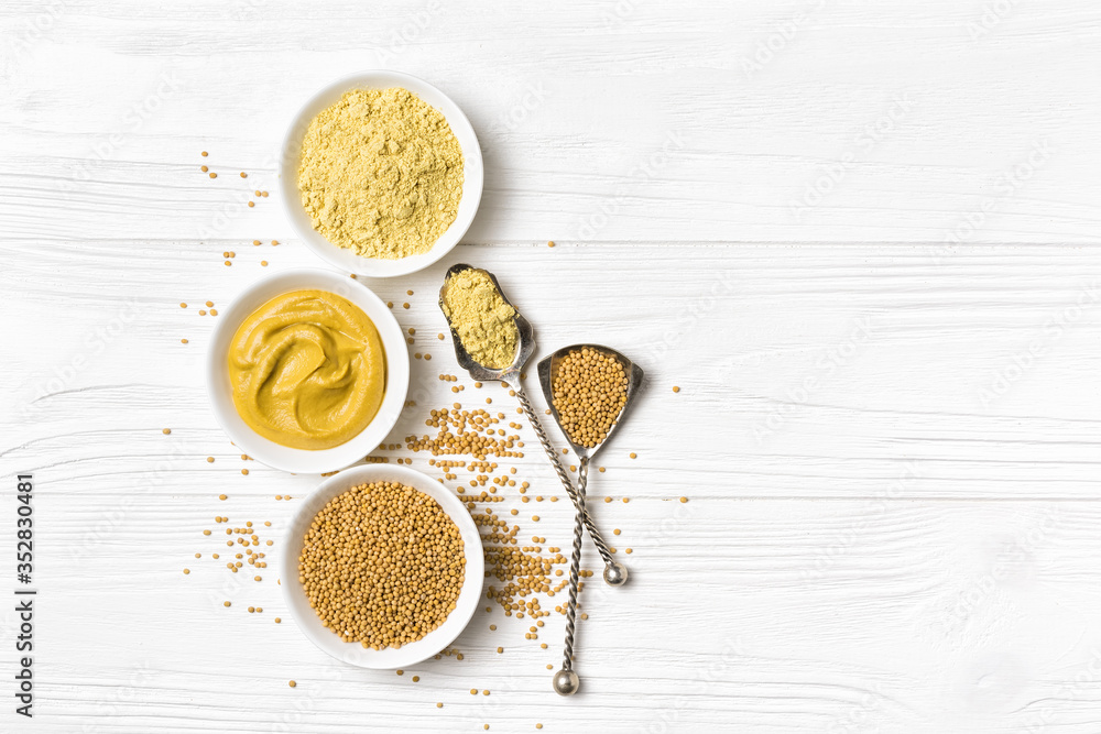Set of yellow mustard sauce, powder and seeds in small bowls with silver spoons - obrazy, fototapety, plakaty 