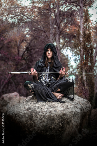 Cuadros en Lienzo Woman in the forest dressed in a tunic as a sorceress holding a large sword