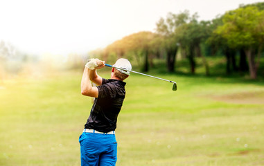 Golfer hit sweeping golf ball on blurred beautiful golf course with sunshine on background.