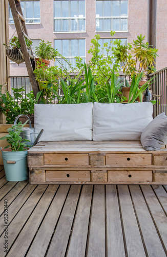 Wooden pallet couch on balcony with plants in background