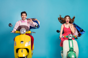 Photo of funny two people lady guy drive rent retro moped travelers hold hands many shopping packs good mood addicted shoppers abroad vintage clothes isolated blue color background