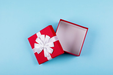 Open red gift box on blue paper background. Top view, flat lay, place for object. Mockup, holiday concept.