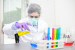 © W PRODUCTION - Young doctor scientist in the laboratory making experience research about covid19 coronavirus vaccine wearing white lab coat a mobcap and surgical mask