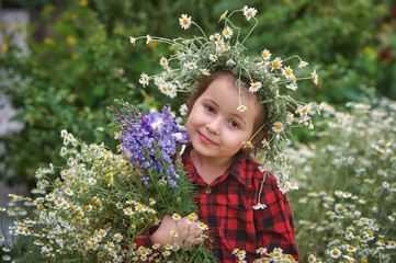 Portrait of a lovely little girl in a wreath of daisies