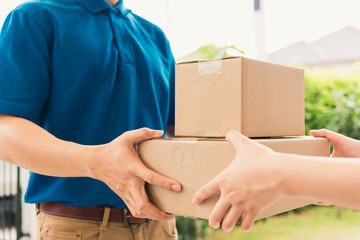 Wall Mural - Asian delivery express courier young man giving boxes to woman customer receiving both protective face mask, under curfew quarantine pandemic coronavirus COVID-19