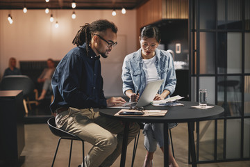 Wall Mural - Two diverse young businesspeople working together at an office t