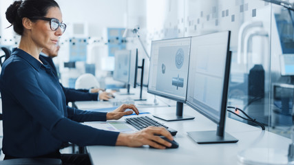 Industrial Engineer Solving Problems, Working on a Personal Computer, Using Mouse and Keyboard, Two Monitor Screens Show CAD Software with Machine Equipment in 3D.