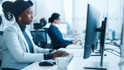 Canvas Print - Beautiful Female Engineer Working on Personal Computer in the High-Tech Industrial Factory. Busy Office on a Factory. Side View Portrait 