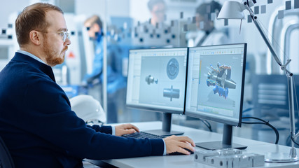 Fototapete - Heavy Industry Engineer Working on Personal Computer, Screen Shows CAD Software with 3D Prototype of Zero-Emissions Engine. Industrial Factory with High-Tech CNC Machinery.