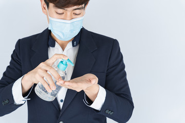 Wall Mural - Asian handsome happy business man wearing a medical protection face mask for protect the coronavirus, filter dust PM 2.5 and cold and using sanitizer hand gel on white background