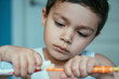 selective focus of adorable boy applying toothpaste on toothbrush