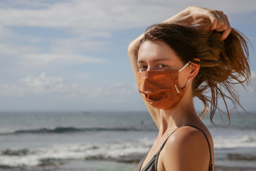 Woman with protective mask on the beach. Summer vacation after Coronavirus pandemic crisis.