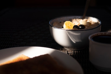 Wall Mural - Oatmeal with bananas and berries in the morning light. Coffee, breakfast.