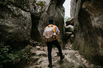 man hiker with a backpack climbs into the mountains by a rocky gorge. travel concept