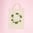 Canvas eco bag with creative green composition made of green spinach leaf, rucola and bean . Flat lay view on pink background