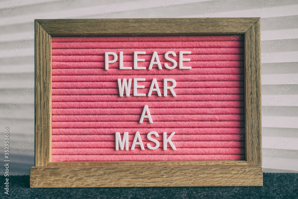 COVID-19 sign PLEASE WEAR A MASK at grocery store entrance for coronavirus prevention. Message on pink felt letter board. Compulsory measure in businesses for face protection wearing. - obrazy, fototapety, plakaty 