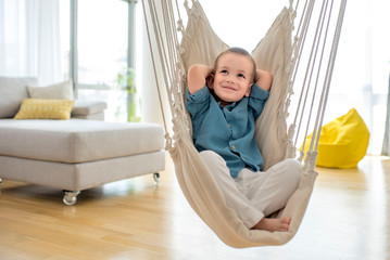 Adorable little boy in comfortable indoor swing relaxing and thinking