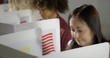 © vesperstock - BCU mature brunette woman, seen from high viewpoint as she casts vote with others at polling station in election