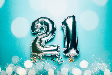 Silver Number Balloons 21 on green background with bokeh lights. Holiday Party Decoration or postcard concept with top view