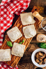 Wall Mural - Homemade fresh Italian ravioli pasta with mushrooms on rustic wooden background.