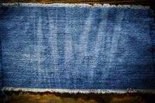 Denim Blue Cloth Frame Patch On Wooden Table. Denim Jeans Frame Background. Ripped Denim Fabric, Text Place, Copy Space. Washed Torn Denim Cloth With Fringe Edge. Fashion Backdrop.