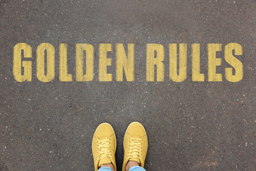 Wall Mural - Woman standing near phrase GOLDEN RULES on asphalt, top view