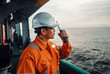 © Igor Kardasov - Filipino deck Officer on deck of vessel or ship , wearing PPE personal protective equipment. He speaks to VHF walkie-talkie radio in hands. Dream work at sea