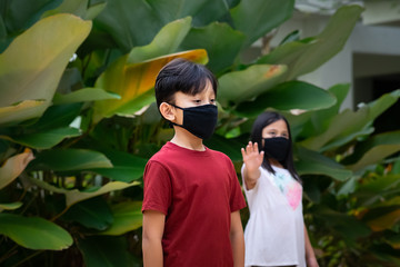 Two Asian children wearing mask standing distance of 1 meter from others keeping distancing. To protect from COVID-19 viruses and people social distancing for infection risk at the playground park.