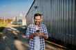© Dusan Petkovic - Young smiling unshaven caucasian farmer standing next to barn and using smart phone for texting.