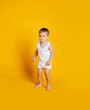 © Julie Boro - Little boy stands in a white T-shirt and underpants on an orange-yellow background