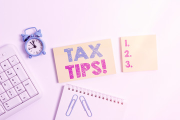 Handwriting text Tax Tips. Conceptual photo compulsory contribution to state revenue levied by government Blank paper with copy space on the table with clock and pc keyboard